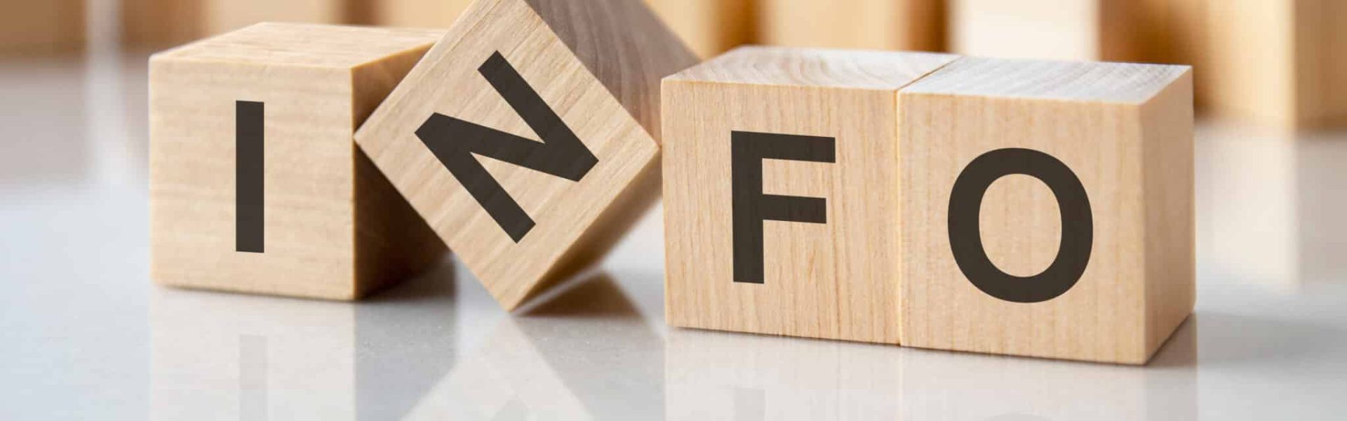 four wooden blocks with the letters info on the bright surface of a gray table. the inscription on the cubes is reflected from the surface of the table